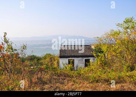 Una vecchia piccola capanna su una montagna nel villaggio di Luxiang in Cina. Dietro la casa si può vedere il mare e l'orizzonte giace nella nebbia. Foto Stock