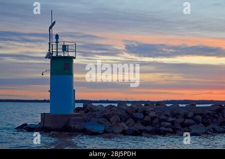 Faro sul bordo di una barriera che segna l'ingresso di un porto turistico Foto Stock