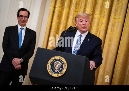 Il presidente degli Stati Uniti Donald J. Trump parla come segretario del Tesoro statunitense Steven T. Mnuchin, ascolta durante un evento del Paycheck Protection Program (PPP) nella stanza orientale della Casa Bianca a Washington, DC, USA, martedì 28 aprile 2020. Il presidente difese la sua risposta prematuro e dismissiva all'epidemia di coronavirus, dicendo martedì che gli fu detto a fine febbraio che non sarebbe stato un problema. Credito: Al Drago/Pool via CNP/MediaPunch Foto Stock