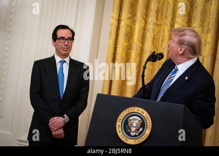 Il presidente degli Stati Uniti Donald J. Trump parla come segretario del Tesoro statunitense Steven T. Mnuchin, ascolta durante un evento del Paycheck Protection Program (PPP) nella stanza orientale della Casa Bianca a Washington, DC, USA, martedì 28 aprile 2020. Il presidente difese la sua risposta prematuro e dismissiva all'epidemia di coronavirus, dicendo martedì che gli fu detto a fine febbraio che non sarebbe stato un problema. Credito: Al Drago/Pool via CNP/MediaPunch Foto Stock