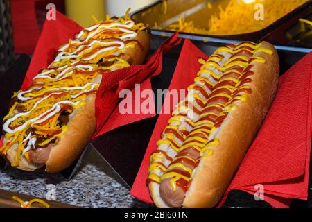 Concetto di cibo di strada, hot dog con salse in mostra sul tovagliolo rosso Foto Stock