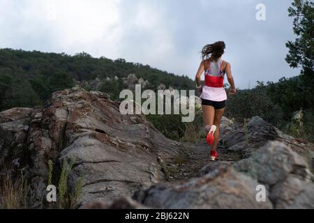 Una donna vista da dietro correre su un sentiero Foto Stock