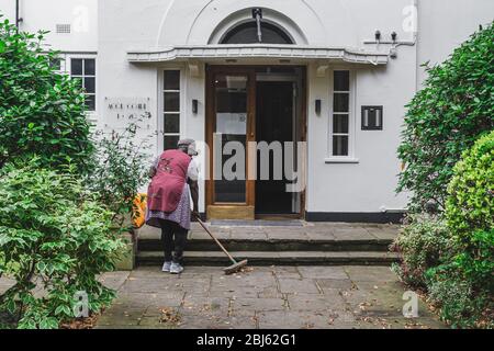 Londra/UK-30/07/18: Una donna che pulisce il pavimento con un pulitore sulla terrazza di un palazzo di appartamenti a Londra Foto Stock