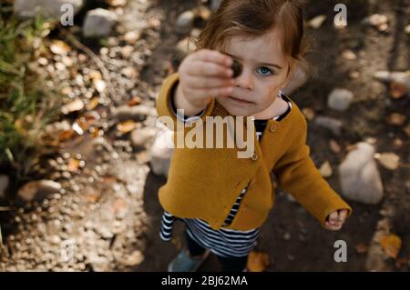 Ragazza giovane che tiene su una roccia che copre il suo occhio dentro la caduta Foto Stock