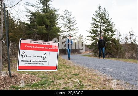 Uomo e ragazzo che camminano su un sentiero boscoso con il cartello Covid 19 su di esso. Foto Stock