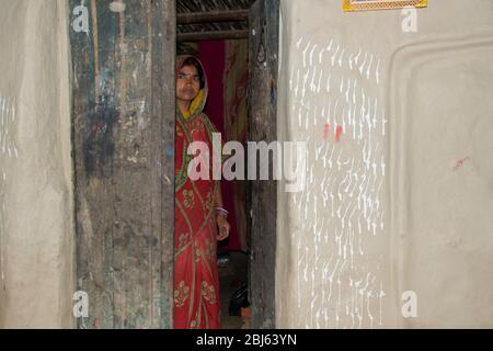 Donna rurale in piedi a casa porta in villaggio, India Foto Stock