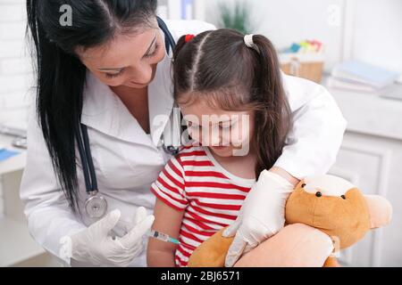 Medico che inietta l'orso giocattolo Foto Stock