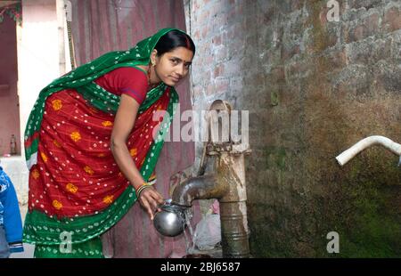 donna rurale che raccoglie acqua potabile da tubewell, india Foto Stock