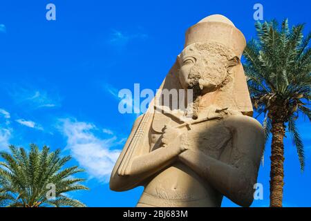 Luxor Egitto. Statua di Ramses II con la figlia Merit-Amon al tempio di Karnak, contro il cielo blu e le palme. Primo piano Foto Stock