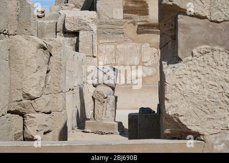 Statua senza testa rovinata sotto le manche di dio Osiride nel complesso del tempio di Karnak Foto Stock