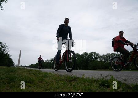 Washington, Stati Uniti. 28 Aprile 2020. La gente viaggia in bicicletta con il Washington Monument sullo sfondo a Washington, DC, Stati Uniti, il 28 aprile 2020. Il numero di casi COVID-19 negli Stati Uniti ha superato 1 milione di martedì pomeriggio, raggiungendo 1,002,498 alle 13:55 (1755 GMT), secondo il Center for Systems Science and Engineering della Johns Hopkins University. Credit: Liu Jie/Xinhua/Alamy Live News Foto Stock