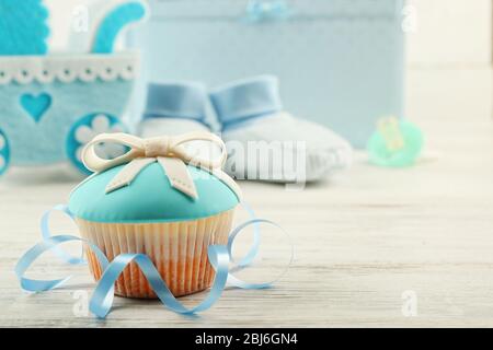 Gustosi cupcake con scarpe da fiocco e da bambino, carrozzina decorativa e album fotografico su sfondo colorato Foto Stock