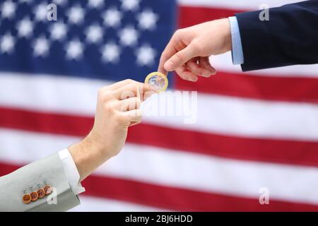 Uno sposo che dà un preservativo ad un altro uomo su sfondo americano bandiera Foto Stock