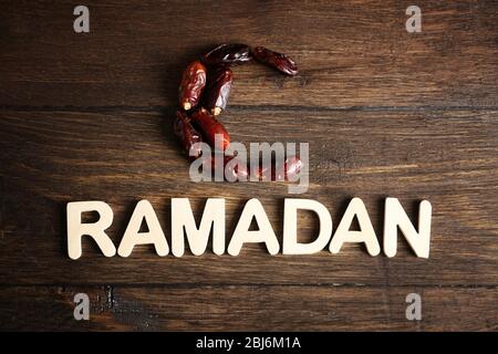 Immagine della parola RAMADAN e datteri frutta su sfondo legno, primo piano Foto Stock