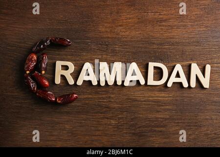 Immagine della parola RAMADAN e datteri frutta su sfondo legno, primo piano Foto Stock