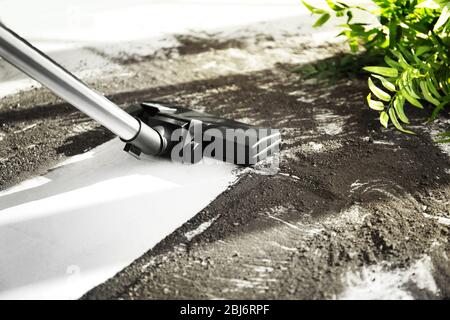 Aspirapolvere dopo caduta vaso di fiori su un pavimento piastrellato Foto Stock