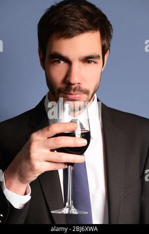 Uomo che sniffa vino rosso in vetro su sfondo blu Foto Stock