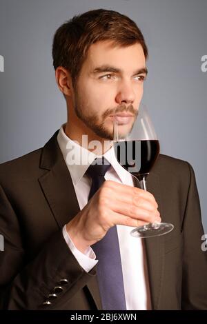 Uomo che sniffa vino rosso in vetro su sfondo blu Foto Stock