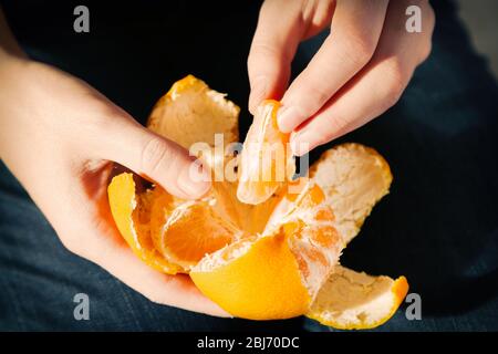 Donna mano peeling maturo dolce mandarino, primo piano Foto Stock