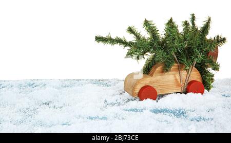 Giocattolo auto in legno con albero di Natale su un tavolo nevoso su sfondo bianco Foto Stock