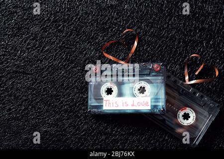 Cassette audio retro con nastri a forma di cuore su sfondo nero testurizzato Foto Stock