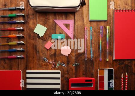 Scuola con taccuini, penne e matite colorate su sfondo in legno Foto Stock