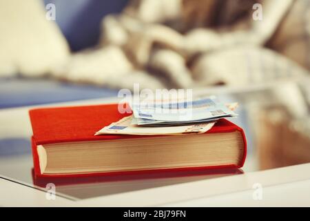 Libro rosso con banconote in euro su un tavolo di vetro Foto Stock