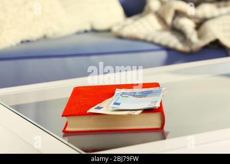 Libro rosso con banconote in euro su un tavolo di vetro Foto Stock