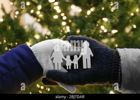 Mani che tengono piccola famiglia statuette su sfondo illuminato Foto Stock