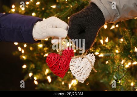 Mani che tengono piccoli cuori su sfondo illuminato Foto Stock