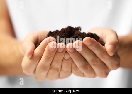 Mani maschili che tengono suolo, closeup Foto Stock