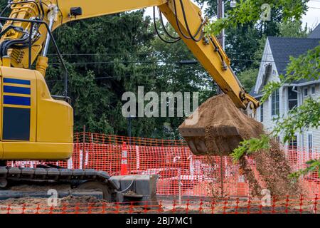 Il caricatore frontale sta scavando in un nuovo cantiere in una zona urbana molto trafficata Foto Stock