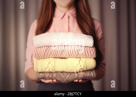 Pila di vestiti a maglia in maglia mani femminili Foto Stock