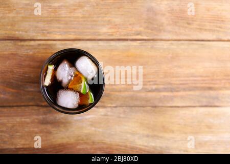 Cocktail con fette di lime e blocchi di ghiaccio su tavolo di legno, vista dall'alto Foto Stock