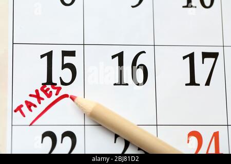 Un contrassegno rosso di imposta nel calendario il giorno 15 con una matita, primo piano Foto Stock