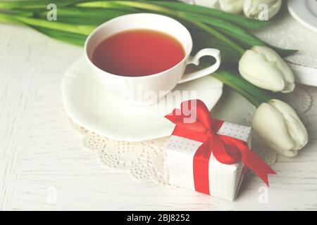 Scatola con tulipani e tazza di tè su tavolo in legno primo piano Foto Stock