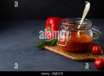 Ajvar, pinjur, lutenitsa, harissa in riva su uno sfondo scuro. Spazio di copia Foto Stock