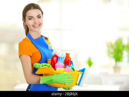 Donna in guanti di gomma con vaschetta di contenimento con detergenti su sfondo sfocato Foto Stock