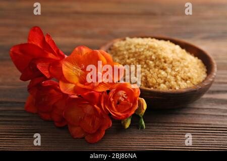 Bellissimi fiori esotici e sale marino in una ciotola su sfondo di legno Foto Stock