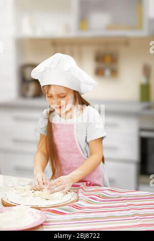 Bella bambina che taglia i cuori da un impasto Foto Stock