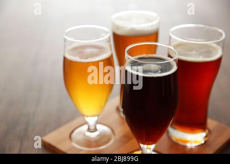 Bicchieri con diversi tipi di birra artigianale su vassoio di legno Foto Stock