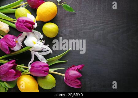 Tulipani viola freschi, iridi e citruse su sfondo nero, vista dall'alto Foto Stock