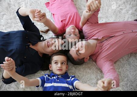Vista dall'alto di un ritratto di famiglia felice sdraiato su un tappeto di pelliccia all'interno Foto Stock
