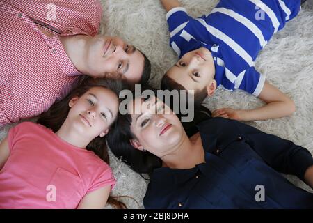 Vista dall'alto di un ritratto di famiglia felice sdraiato su un tappeto di pelliccia all'interno Foto Stock