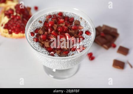 Budino di semi di Chia con granelli di melograno e patatine di cioccolato in piattino di vetro su fondo bianco Foto Stock