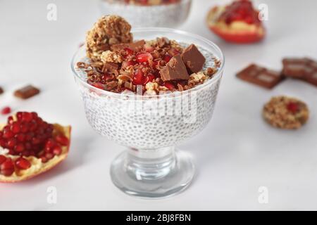 Budino di semi di Chia con granelli di melograno e patatine di cioccolato in piattino di vetro su fondo bianco Foto Stock