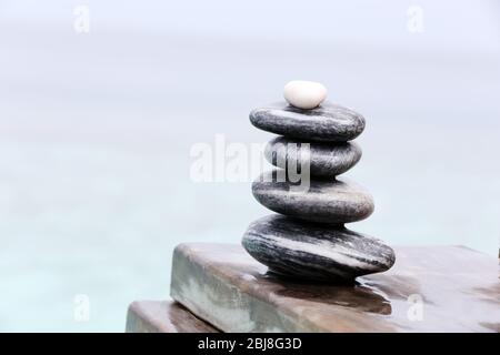 Pila di pietre termali su ponte bagnato in legno Foto Stock