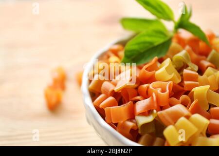 Pasta secca multicolore a forma di cuore in ciotola bianca, primo piano Foto Stock