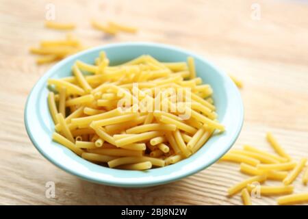 Pasta secca in piatti blu su tavola di legno Foto Stock