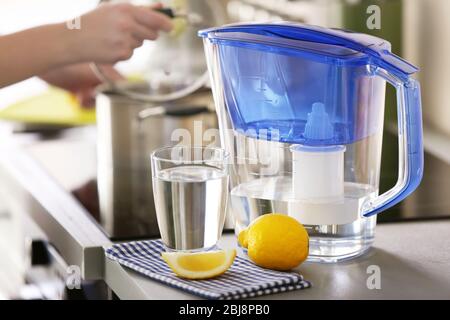 Bicchiere con filtro dell'acqua al limone e vetro sul tavolo da cucina Foto Stock